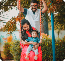 Photo of a mother, father and child swinging on swing and smiling